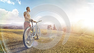 Cycling. Man with bike on a forest road in the mountains on a summer day. Mountain valley during sunrise. Sport