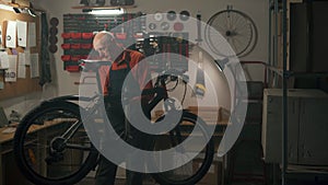 Cycling mechanic fixing bicycle, cleaning wheel in workshop. Elderly caucasian repairman. Bike service, repair and