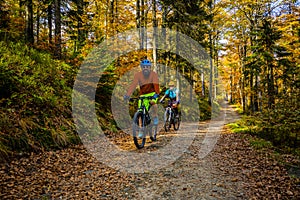 Cycling, mountain biker couple on cycle trail in autumn forest. Mountain biking in autumn landscape forest. Man and woman cycling photo