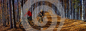 Cycling, mountain biker couple on cycle trail in autumn forest. Mountain biking in autumn landscape forest. Man and woman cycling