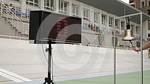 Cycling referee rings bell on velodrome. Lap screen on cycling track. Electronic board with indicator of number of laps to finish.