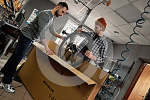 Cycling servicemen take wheel of bicycle from box