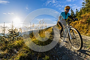 Cycling woman riding on bike in autumn forest landscape. Woman cycling MTB flow trail track. Outdoor sport activity