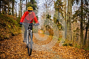 Cycling woman riding on bike in autumn forest landscape. Woman cycling MTB flow trail track. Outdoor sport activity