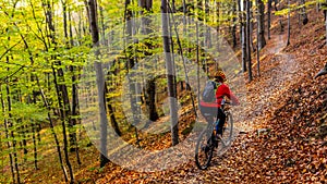 Cycling woman riding on bike in autumn forest landscape. Woman cycling MTB flow trail track. Outdoor sport activity