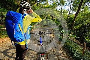 Cyclist adjust the helmet belt before riding mountain bike on forest trail