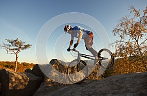 Cyclist balancing on front wheel on trial bicycle on boulder