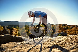Cyclist balancing on front wheel on trial bicycle on boulder