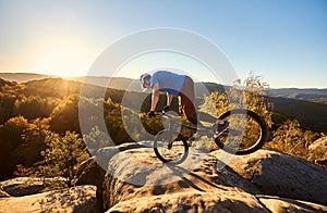 Cyclist balancing on front wheel on trial bicycle on boulder