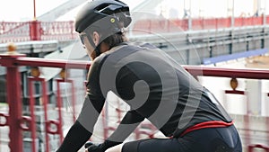 Cyclist on bicycle with bridge on the background. Easy ride on road bike in the city park. Back follow shot. Slow motion