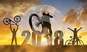 Cyclist with bicycle at sunset. New Year 2018 concept.