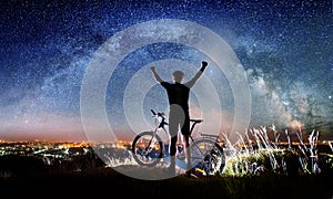 Cyclist with bike in the night under starry sky