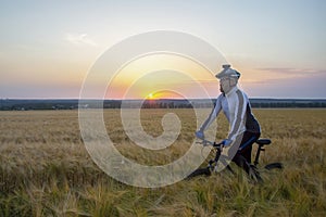 Cyclist on bike rides along the fields of wheat in the sunlight. sports and hobbies. outdoor activities