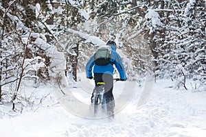 Cyclist in Blue Drifting on Mountain Bike in Beautiful Winter Forest. Extreme Sport and Enduro Biking Concept.