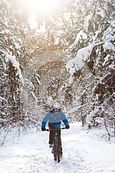 Cyclist in Blue Riding the Mountain Bike in Beautiful Sunny Winter Forest. Extreme Sport and Enduro Biking Concept.
