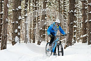 Cyclist in Blue Riding the Mountain Bike in Beautiful Winter Forest. Extreme Sport and Enduro Biking Concept.