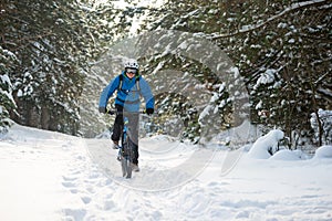 Cyclist in Blue Riding the Mountain Bike in Beautiful Winter Forest. Extreme Sport and Enduro Biking Concept.