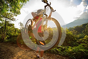 Cyclist carrying mountain bike climbing on summer forest trail