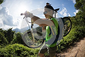 Cyclist carrying mountain bike on mountain trail