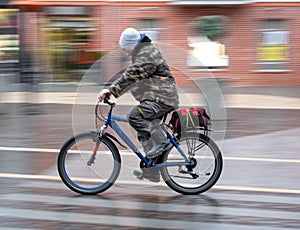Cyclist on the city roadway in motion blur in rainy day. Intentional motion blur