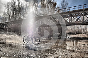 Cyclist crosses a stream with his bike and churns up the water.