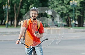 Cyclist with delivery. Happy courier with backpack, smart watch and smartphone, sits on bicycle
