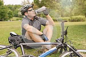 Cyclist drinks water from a bottle while resting