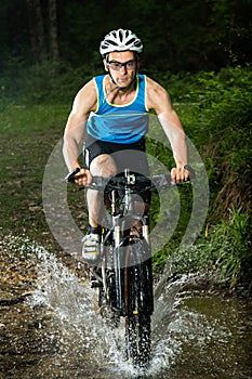 A cyclist driving through a streambed