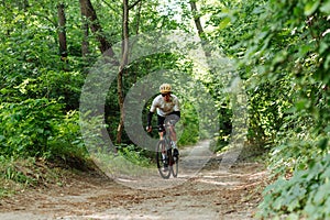 Cyclist in full gear rides on forest trails on a gravel bicycle