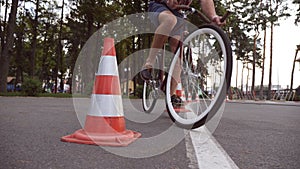 Cyclist go round traffic cones. Young handsome man riding a vintage bicycle. Sporty guy cycling at the park. Healthy