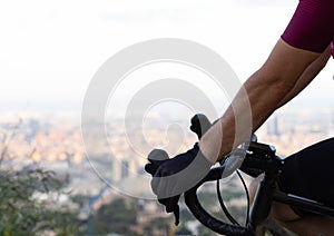 Cyclist grasping the handlebars of a road bike observing the city of Barcelona