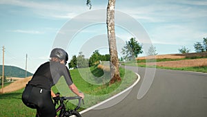 Cyclist in helmet cycling on bicycle. Cycling at sunset. Triathlete training and preparing for bike race competition. Female cycli