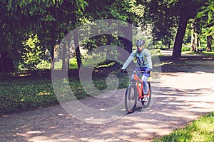 Cyclist in helmet on orange bike riding in park