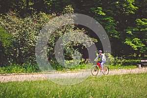 Cyclist in helmet on orange bike riding in park