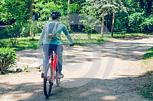 Cyclist in helmet on orange bike riding in park