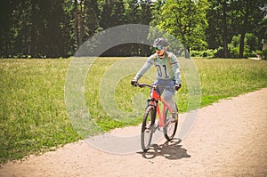 Cyclist in helmet on orange bike riding in park