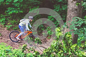 A cyclist in a helmet is riding off-road, motion blur