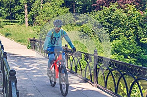 Cyclist in helmet riding in park on bridge