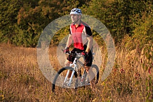 Cyclist with His Bike on the Autumn Meadow