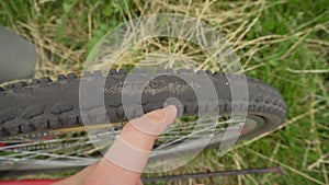 A cyclist inspects an old punctured tire on a bicycle wheel, outdoor