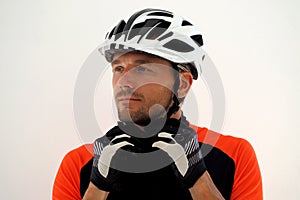 Cyclist in jersey fastens the straps on his helmet.