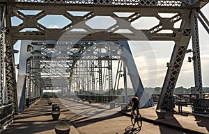 Cyclist on John Seigenthaler pedestrian bridge or Shelby street crossing at sunrise in Nashville