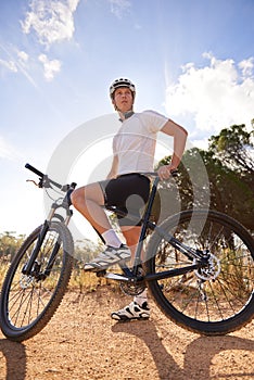 Cyclist, man and bicycle ride in outdoors, hill and mountain biking in countryside. Male person, freedom and cardio for