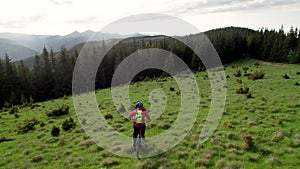 Cyclist man riding electric mountain bike outdoors along grassy trail in the mountains.