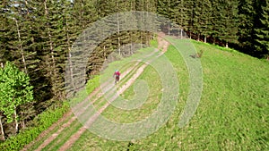 Cyclist man riding electric mountain bike outdoors along grassy trail in the mountains.