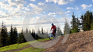 Cyclist man riding electric mountain bike outdoors along grassy trail in the mountains.