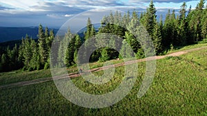 Cyclist man riding electric mountain bike outdoors along grassy trail in the mountains.