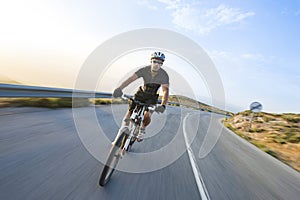 Cyclist man riding mountain bike in sunny day