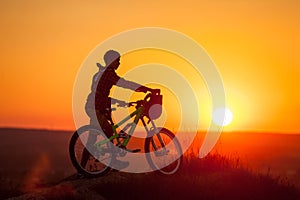 Cyclist with mountain bike on the hill in the evening