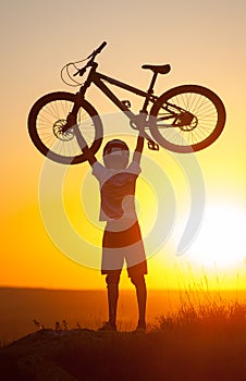 Cyclist with mountain bike on the hill in the evening